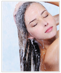Woman washing shampoo from hair.